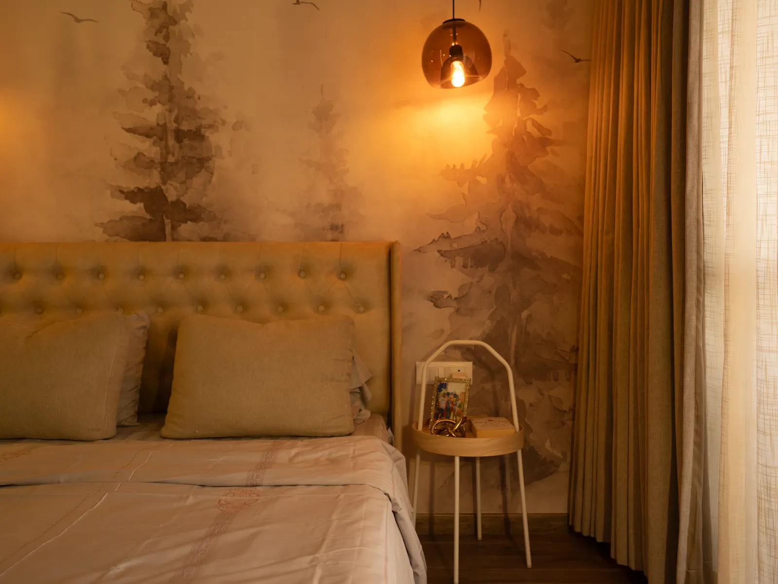 Tufted headboard and bedside pendant against forest wallpaper — Amlan's Residence